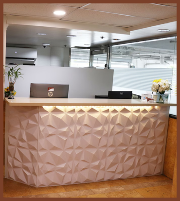 Reception desk with a white marble top at Hometel Suites, showcasing a welcoming atmosphere for affordable stays.